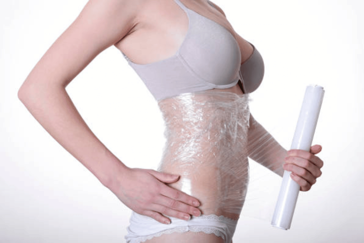 Woman wrapping plastic film around her torso to illustrate neoprene/plastic wrap use